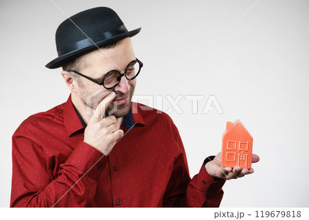 Man wearing funny eyeglasses holding house 119679818