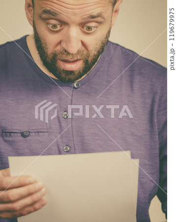 Shocked man looking at documents Shocked man looking at documents 119679975