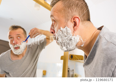 Guy shaving his beard in bathroom 119680171