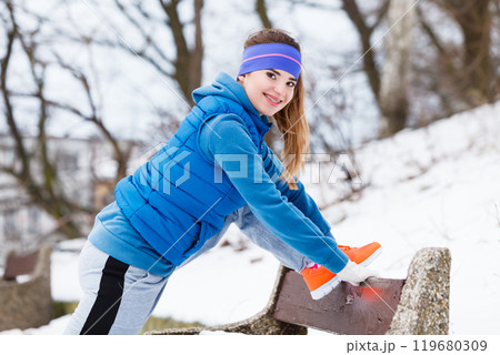 Woman wearing sportswear exercising outside during winter 119680309