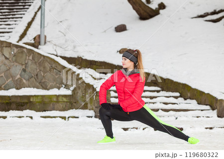 Woman wearing sportswear exercising outside during winter Woman wearing sportswear exercising outside during winter 119680322
