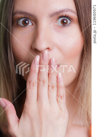 Shy speechless woman covering mouth with hand. 119680971