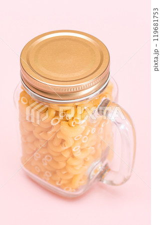 Uncooked Chifferi Rigati Pasta in Glass Jar on Pink Background 119681753