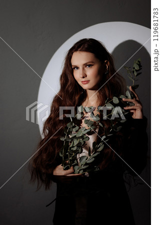 Woman holding leafy plant in hand in circle of light 119681783