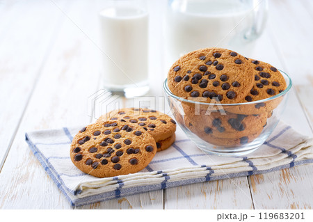 Chocolate chip cookies and a jug of fresh milk on a light kitchen table,healthy breakfast. Chocolate chip cookies and a jug of fresh milk on a light kitchen table,healthy breakfast. 119683201