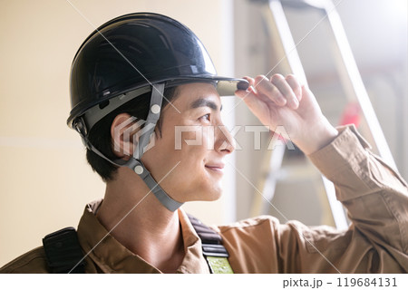 ヘルメットを被る見上げる現場作業員のクローズアップ 119684131