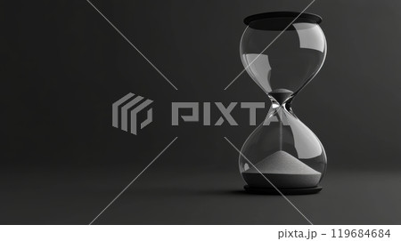 A glass hourglass with sand in it is sitting on a dark background 119684684