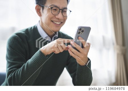 スマートフォンを持った30代後半の男性の手元 スマートフォンを持った30代後半の男性の手元 119684978