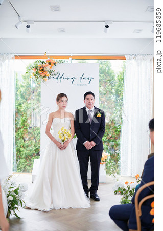 Small wedding - the priest is present, the bride and groom hold their wedding bouquets, hold hands, and share a beautiful moment with family and friends. 119685859