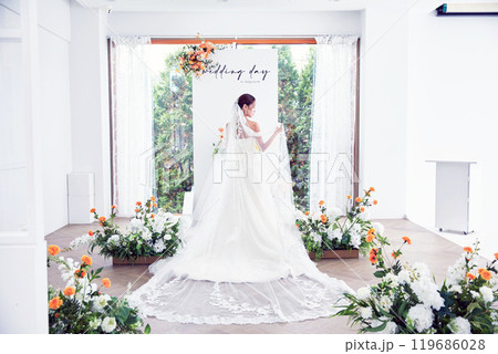 Small wedding - the priest is present, the bride and groom hold their wedding bouquets, hold hands, and share a beautiful moment with family and friends. 119686028