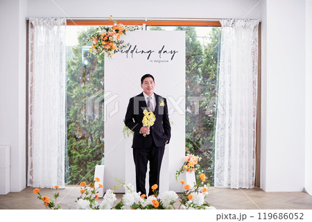 Small wedding - the priest is present, the bride and groom hold their wedding bouquets, hold hands, and share a beautiful moment with family and friends. 119686052