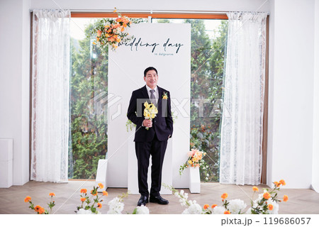 Small wedding - the priest is present, the bride and groom hold their wedding bouquets, hold hands, and share a beautiful moment with family and friends. Small wedding - the priest is present, the bride and groom hold their wedding bouquets, hold hands, and share a beautiful moment with family and friends. 119686057