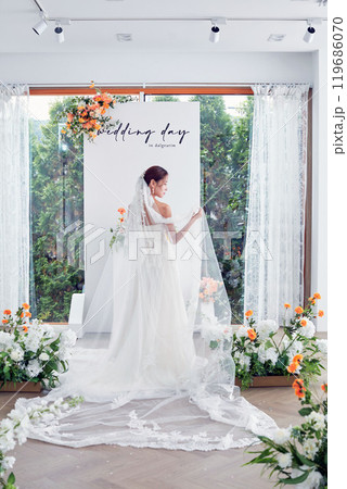 Small wedding - the priest is present, the bride and groom hold their wedding bouquets, hold hands, and share a beautiful moment with family and friends. 119686070