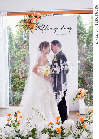 Small wedding - the priest is present, the bride and groom hold their wedding bouquets, hold hands, and share a beautiful moment with family and friends. Small wedding - the priest is present, the bride and groom hold their wedding bouquets, hold hands, and share a beautiful moment with family and friends. 119686086