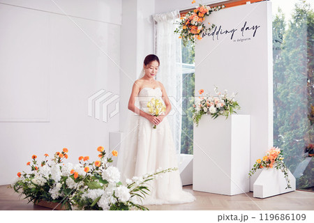 Small wedding - the priest is present, the bride and groom hold their wedding bouquets, hold hands, and share a beautiful moment with family and friends. Small wedding - the priest is present, the bride and groom hold their wedding bouquets, hold hands, and share a beautiful moment with family and friends. 119686109