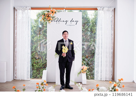 Small wedding - the priest is present, the bride and groom hold their wedding bouquets, hold hands, and share a beautiful moment with family and friends. Small wedding - the priest is present, the bride and groom hold their wedding bouquets, hold hands, and share a beautiful moment with family and friends. 119686141