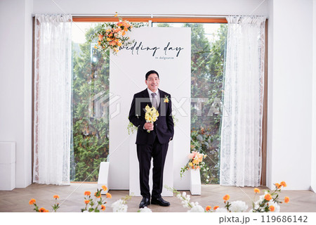 Small wedding - the priest is present, the bride and groom hold their wedding bouquets, hold hands, and share a beautiful moment with family and friends. Small wedding - the priest is present, the bride and groom hold their wedding bouquets, hold hands, and share a beautiful moment with family and friends. 119686142