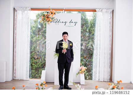 Small wedding - the priest is present, the bride and groom hold their wedding bouquets, hold hands, and share a beautiful moment with family and friends. Small wedding - the priest is present, the bride and groom hold their wedding bouquets, hold hands, and share a beautiful moment with family and friends. 119686152