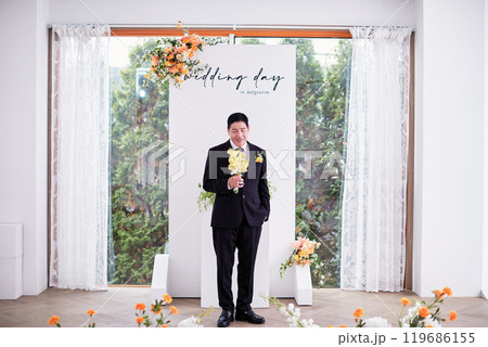 Small wedding - the priest is present, the bride and groom hold their wedding bouquets, hold hands, and share a beautiful moment with family and friends. Small wedding - the priest is present, the bride and groom hold their wedding bouquets, hold hands, and share a beautiful moment with family and friends. 119686155