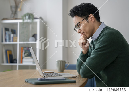 ノートパソコンの前で考え込むアラフォーの男性 119686528