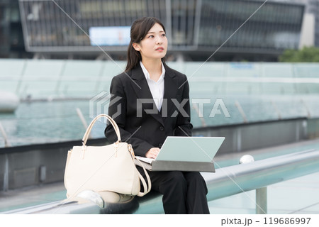 屋外でノートパソコンで作業しながら悩む若いビジネスウーマン 屋外でノートパソコンで作業しながら悩む若いビジネスウーマン 119686997