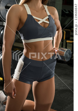 Muscular female exercising with dumbbell 119688647