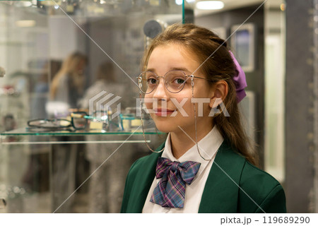 Young girl trying on glasses at an optical store 119689290