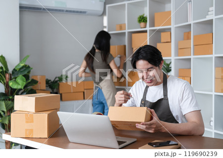 Young Couple Packing Boxes of Merchandise for Online Business in Modern Home Office Young Couple Packing Boxes of Merchandise for Online Business in Modern Home Office 119690239