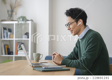 イヤホンをつけてノートパソコンに向かうアラフォーの男性 イヤホンをつけてノートパソコンに向かうアラフォーの男性 119691191