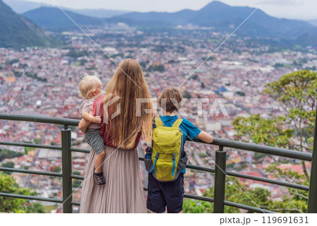 Mom and her two sons, a baby and a teenager tourists in front of the panoramic view of Orizaba from Cerro del Borrego, Mexico. Travel, scenic landscape, and adventure concept Mom and her two sons, a baby and a teenager tourists in front of the panoramic view of Orizaba from Cerro del Borrego, Mexico. Travel, scenic landscape, and adventure concept 119691631