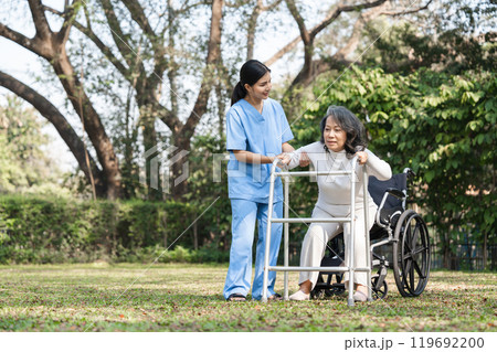 Elderly Woman in Rehabilitation with Caregiver Assistance Outdoors in a Park Setting 119692200