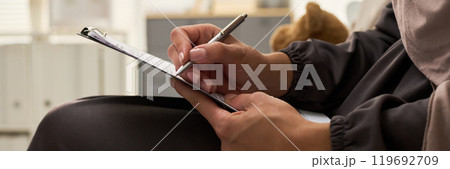 Close-Up of Hands Writing on Clipboard 119692709