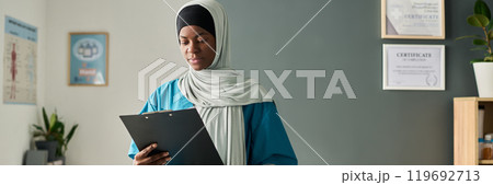 Professional Muslim Woman in Hijab Analyzing Document 119692713