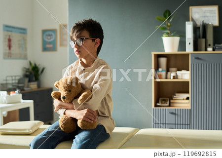 Young Boy Holding Teddy Bear in Modern Room Setting 119692815