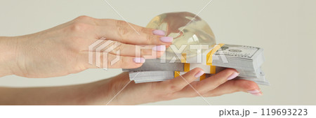 Woman holds silicone breast implants and money in studio Woman holds silicone breast implants and money in studio 119693223