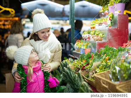 Happy mom with daughter buy spruce twigs for Christmas celebration Happy mom with daughter buy spruce twigs for Christmas celebration 119694891
