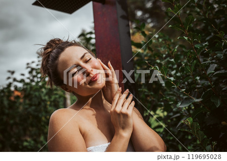 Beautiful woman resting in garden after using home sauna. Woman taking care of her body and mind, wellness routine. Beautiful woman resting in garden after using home sauna. Woman taking care of her body and mind, wellness routine. 119695028