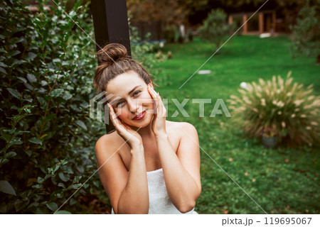 Beautiful woman resting in garden after using home sauna. Woman taking care of her body and mind, wellness routine. Beautiful woman resting in garden after using home sauna. Woman taking care of her body and mind, wellness routine. 119695067