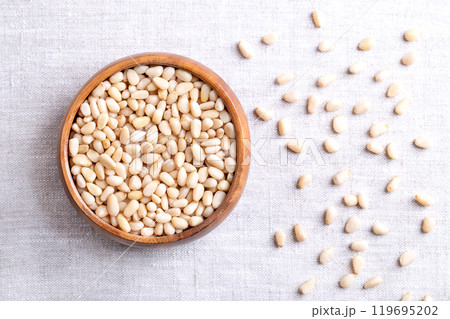 Pine nuts in a wooden bowl on linen fabric. Also known as pinon, pinoli, or pignoli. Shelled seeds and fruits of Korean pines, Pinus koraiensis. Used for pesto, added to dishes or baked into bread. Pine nuts in a wooden bowl on linen fabric. Also known as pinon, pinoli, or pignoli. Shelled seeds and fruits of Korean pines, Pinus koraiensis. Used for pesto, added to dishes or baked into bread. 119695202