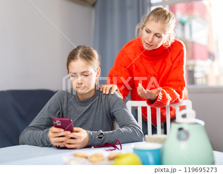 Girl sitting with phone, ignoring mother 119695273