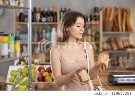Young girl is choosing canned food in grocery store 119695291