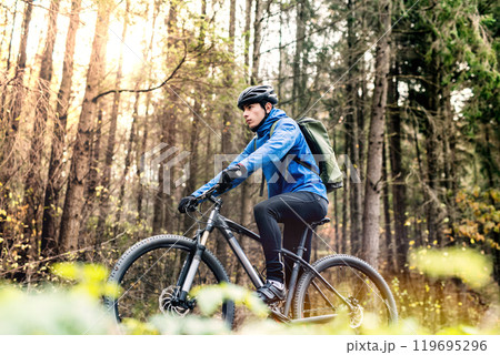 Active man on bike in the middle of beautiful forest, early autumn morning. Concept of healthy lifestyle. Low angle view. Active man on bike in the middle of beautiful forest, early autumn morning. Concept of healthy lifestyle. Low angle view. 119695296