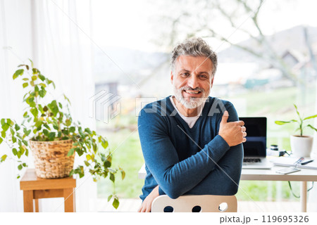 Homeoffice for handsome man. Man sitting on chair backward, looking at camera. Telecommuting. Homeoffice for handsome man. Man sitting on chair backward, looking at camera. Telecommuting. 119695326