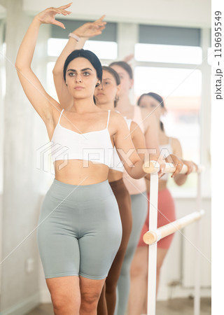 Young female ballet student mastering third position at barre 119695549