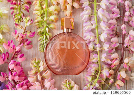 round brown cosmetic perfume bottle and lupine flowers on wooden background. Mockup, spring summer flat lay. glass perfume bottle for branding and label 119695560