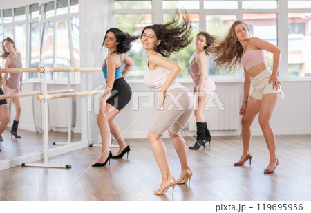 Girls in heels learn to move to beat of music and combine rhythm and smooth movements Girls in heels learn to move to beat of music and combine rhythm and smooth movements 119695936