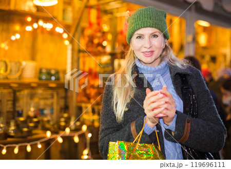 Portrait of woman with a cup of hot coffee at christmas street fair evening Portrait of woman with a cup of hot coffee at christmas street fair evening 119696111