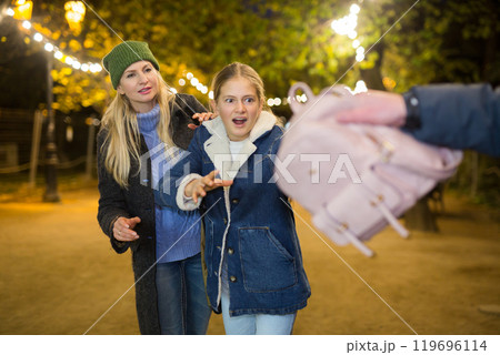 Street thief stealing backpack of scared teenage girl walking with mother Street thief stealing backpack of scared teenage girl walking with mother 119696114