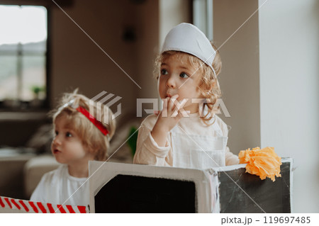Siblings in doctor uniform is playing hospital. Little ambulance paramedics sitting in cardboard ambulance. Siblings in doctor uniform is playing hospital. Little ambulance paramedics sitting in cardboard ambulance. 119697485