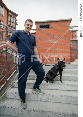 Caucasian man with a pitbull terrier dog sitting on the stairs. Caucasian man with a pitbull terrier dog sitting on the stairs. 119698852